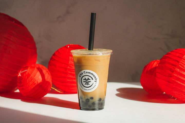 Cha Community boba milk tea with red Chinese lanterns displayed in the background