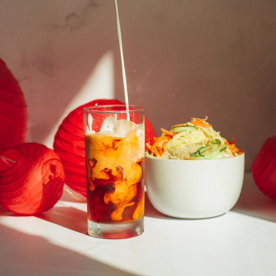Milky Way Thai Tea with cream and Taiwanese Cold Noodles in front of an assortment of Red Chinese lanterns decor